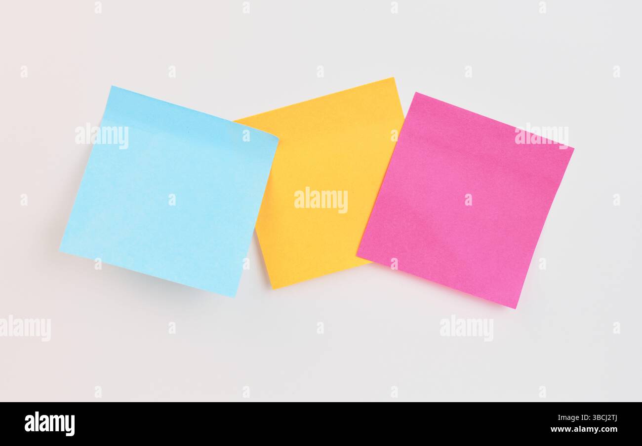 Trois notes adhésives en bleu, jaune et rose sont affichées de manière créative Banque D'Images