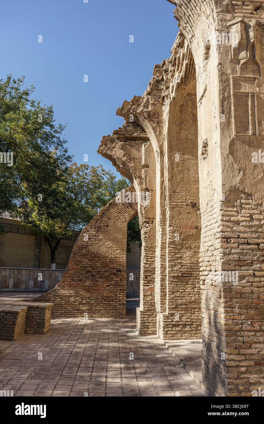 Des ruines de pierre et des briques encadrent l'entrée du mausolée Gur-e-Amir à Samarcande, en Ouzbékistan, avec la lumière du soleil illuminant le site historique. Banque D'Images