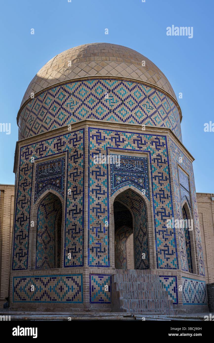 Une tour cylindrique recouverte de tuiles bleues et blanches fait partie du mausolée octogonal de Shah-i-Zinda à Samarcande, Ouzbékistan, sous la lumière du soleil. Banque D'Images
