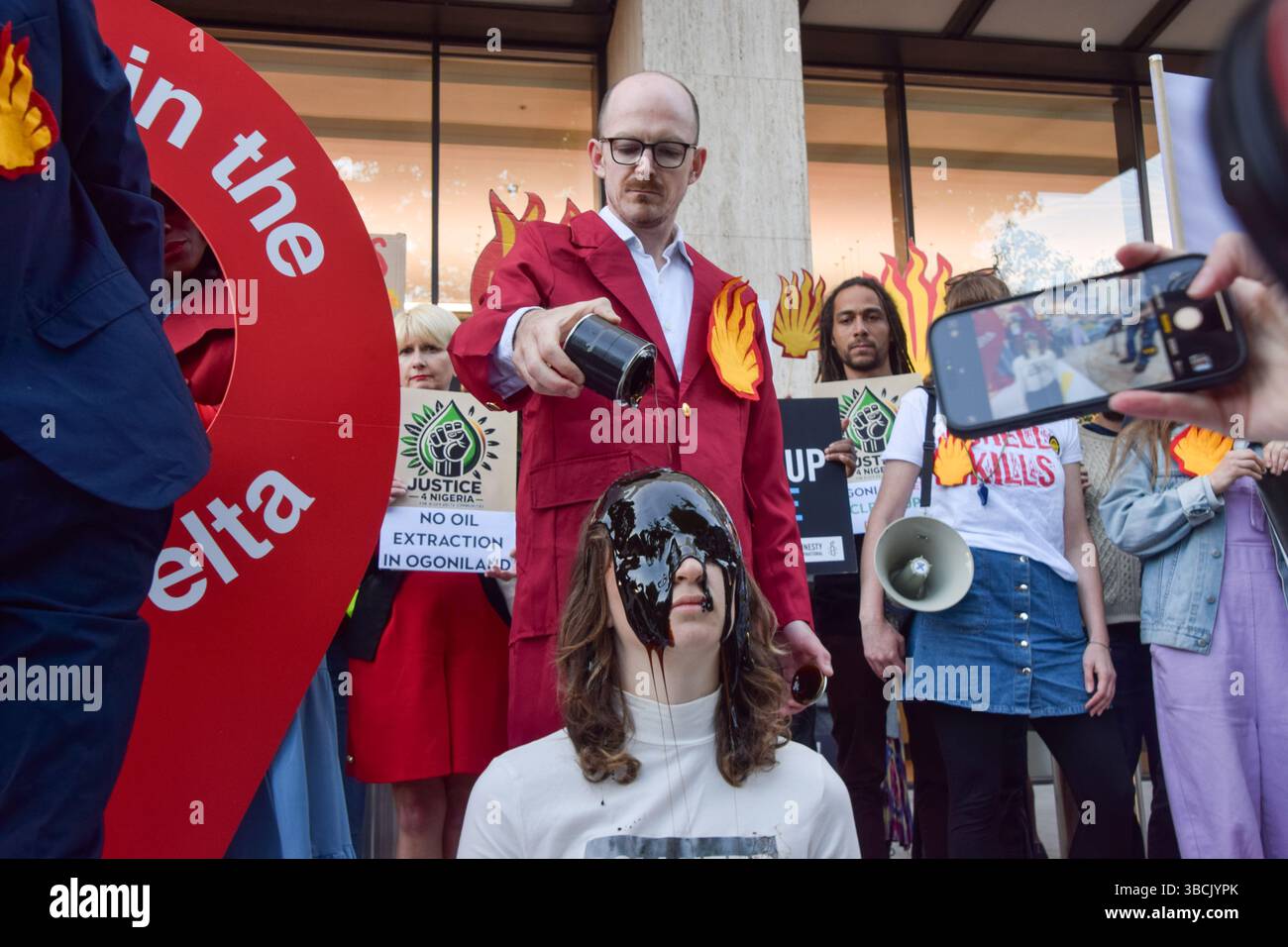 Londres, Royaume-Uni. 20 mai 2025. Un activiste verse de l'huile fausse sur la tête d'un autre activiste pendant la manifestation. Les militants écologistes se sont rassemblés devant le siège de Shell le jour de l'Assemblée générale annuelle (AGA) du géant des combustibles fossiles, qui s'est tenue à Heathrow où les manifestations sont interdites. Les manifestants exigent que Shell nettoie et verse des indemnités pour ses marées noires dévastatrices dans le delta du Niger au Nigeria. Crédit : SOPA images Limited/Alamy Live News Banque D'Images