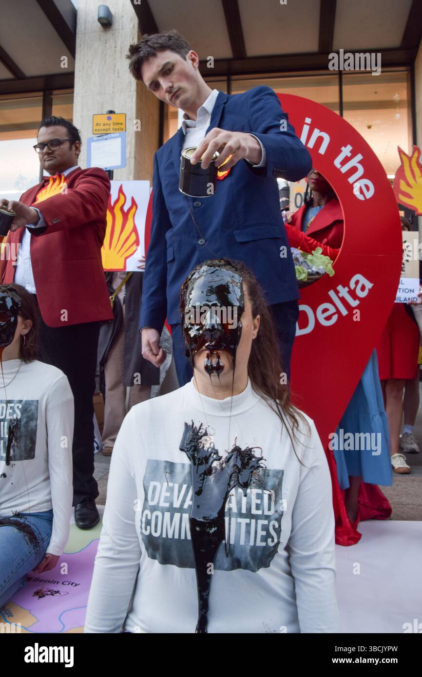 Londres, Royaume-Uni. 20 mai 2025. Un activiste verse de l'huile fausse sur la tête d'un autre activiste pendant la manifestation. Les militants écologistes se sont rassemblés devant le siège de Shell le jour de l'Assemblée générale annuelle (AGA) du géant des combustibles fossiles, qui s'est tenue à Heathrow où les manifestations sont interdites. Les manifestants exigent que Shell nettoie et verse des indemnités pour ses marées noires dévastatrices dans le delta du Niger au Nigeria. Crédit : SOPA images Limited/Alamy Live News Banque D'Images