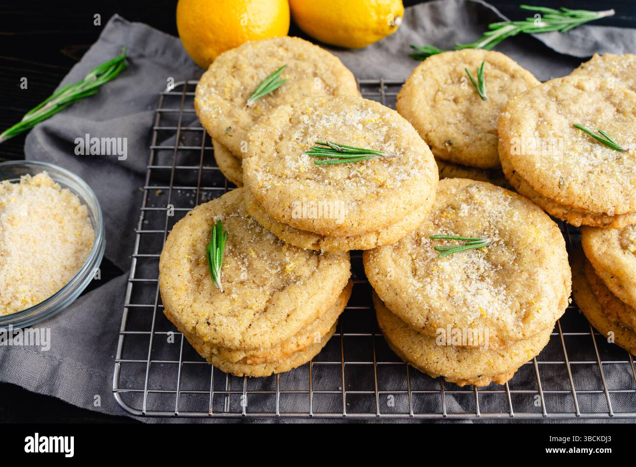 Biscuits au sucre au romarin et au citron empilés sur une grille métallique : vue rapprochée en angle de piles de biscuits au sucre faits maison fraîchement cuits sur une grille de refroidissement métallique Banque D'Images