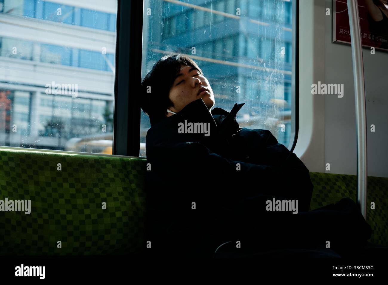 Moment calme de repos dans le métro de Tokyo tandis que la lumière du soleil filtre à travers la fenêtre Banque D'Images