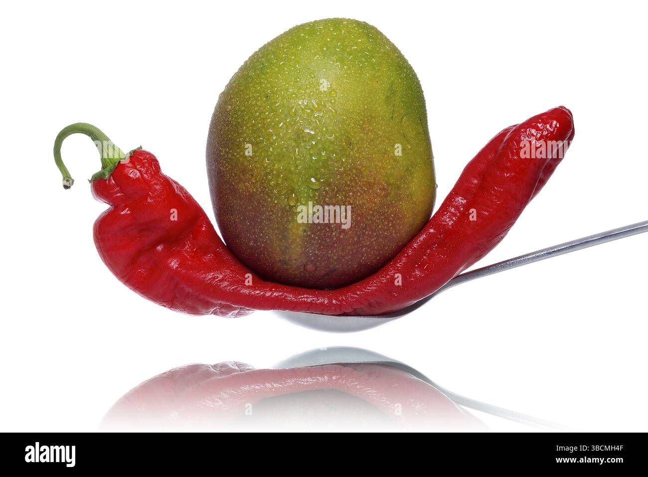 Les fruits de mangue écrasent un poivron sur une cuillère, isolé sur blanc Banque D'Images