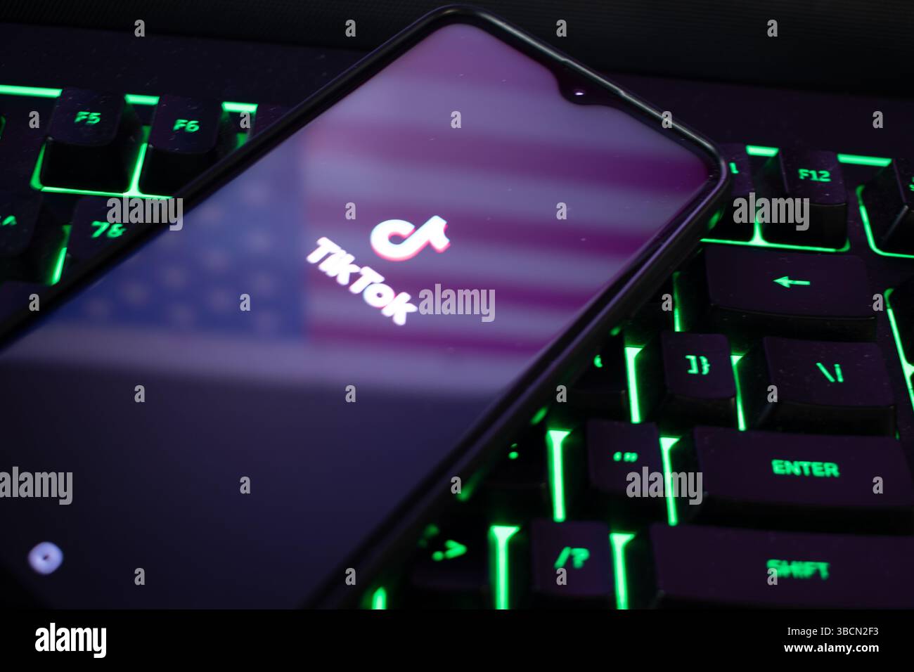 San Fran, CA, 20 mai 2025 : smartphone sur le clavier montre le logo TikTok et reflète le drapeau américain, symbolisant l'impact de l'application sur la culture numérique américaine. Banque D'Images