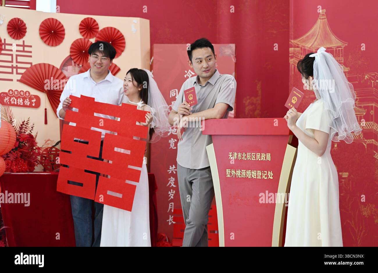 Pékin, Chine. 20 mai 2025. Des jeunes mariés posent pour des photos devant un registre de mariage dans le district de Beichen, dans le nord de la Chine, Tianjin, le 20 mai 2025. La date du 20 mai a une signification particulière en Chine, car sa prononciation chinoise '520' ressemble à l'expression 'WO ai Nin', qui signifie 'je t'aime'. C'est une période de pointe pour les enregistrements de mariage, voyant de longues files d'attente dans les registres de mariage à l'échelle nationale. Crédit : Li Ran/Xinhua/Alamy Live News Banque D'Images