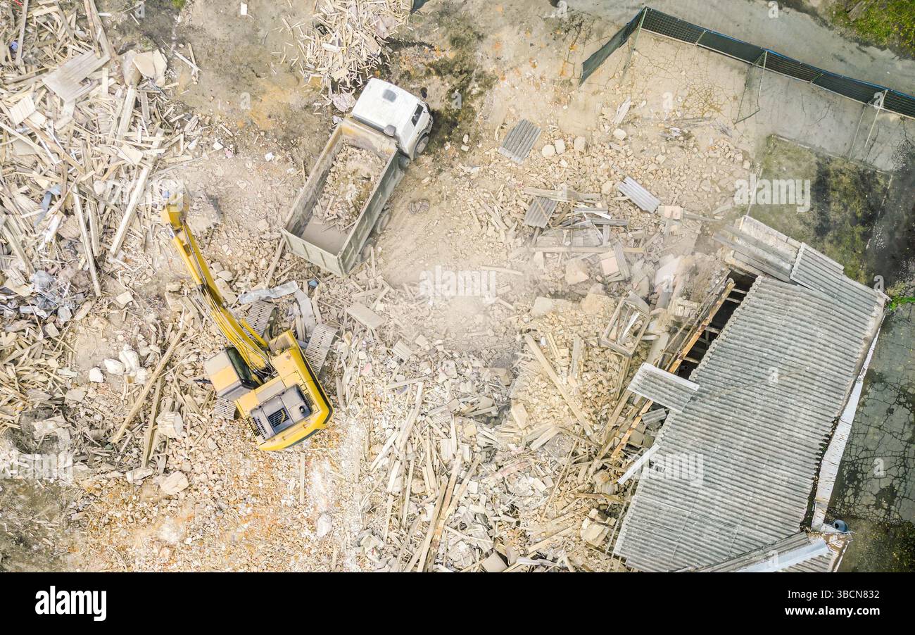 pelle hydraulique travaillant sur le site de démolition et chargeant des débris dans le tombereau à benne basculante. vue aérienne. Banque D'Images