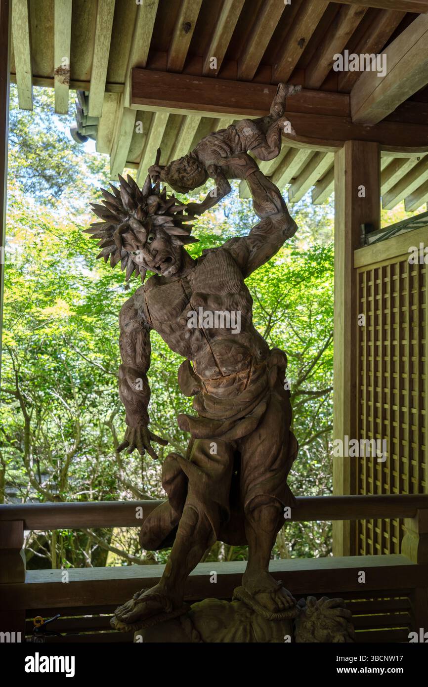 Statue de démon Oni en bois finement sculptée au temple Mitaki-Dera à Hiroshima, représentant une expression féroce et une pose dynamique sous un bois traditionnel Banque D'Images
