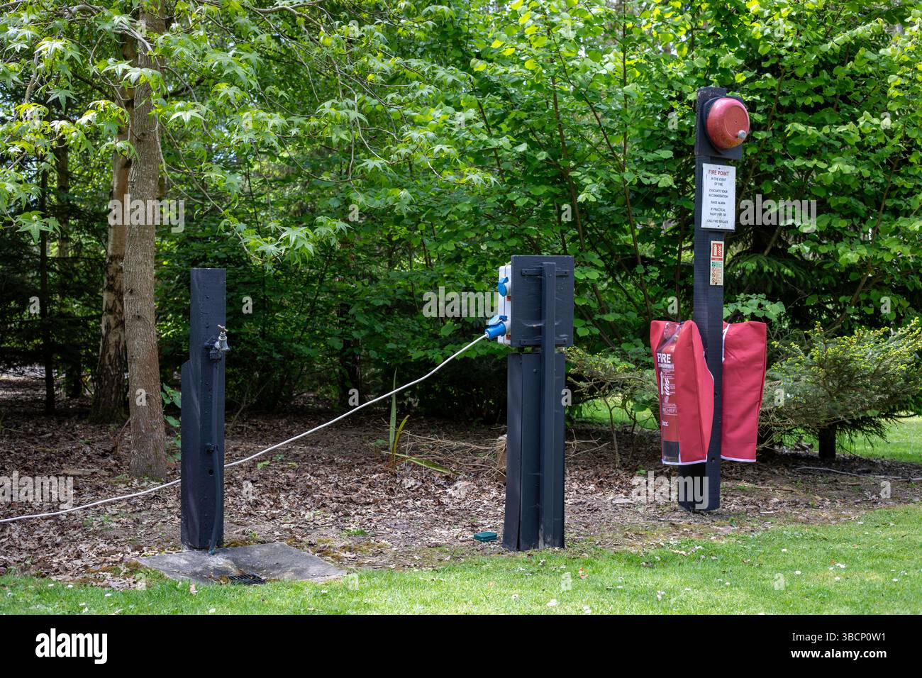 Un robinet d'eau, une prise électrique et un point de feu dans un camping forestier Banque D'Images