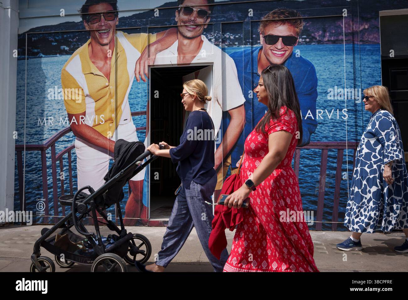Acheteurs et publicité sur la Kings Road, le 20 mai 2025, à Londres, Angleterre. Banque D'Images