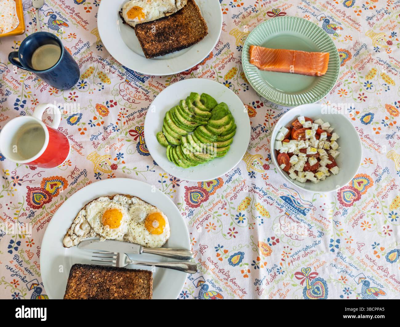 Savourez un brunch maison avec œufs frits, pain grillé, avocat frais, salade de fromage et saumon fumé, idéal pour une matinée paresseuse. Banque D'Images