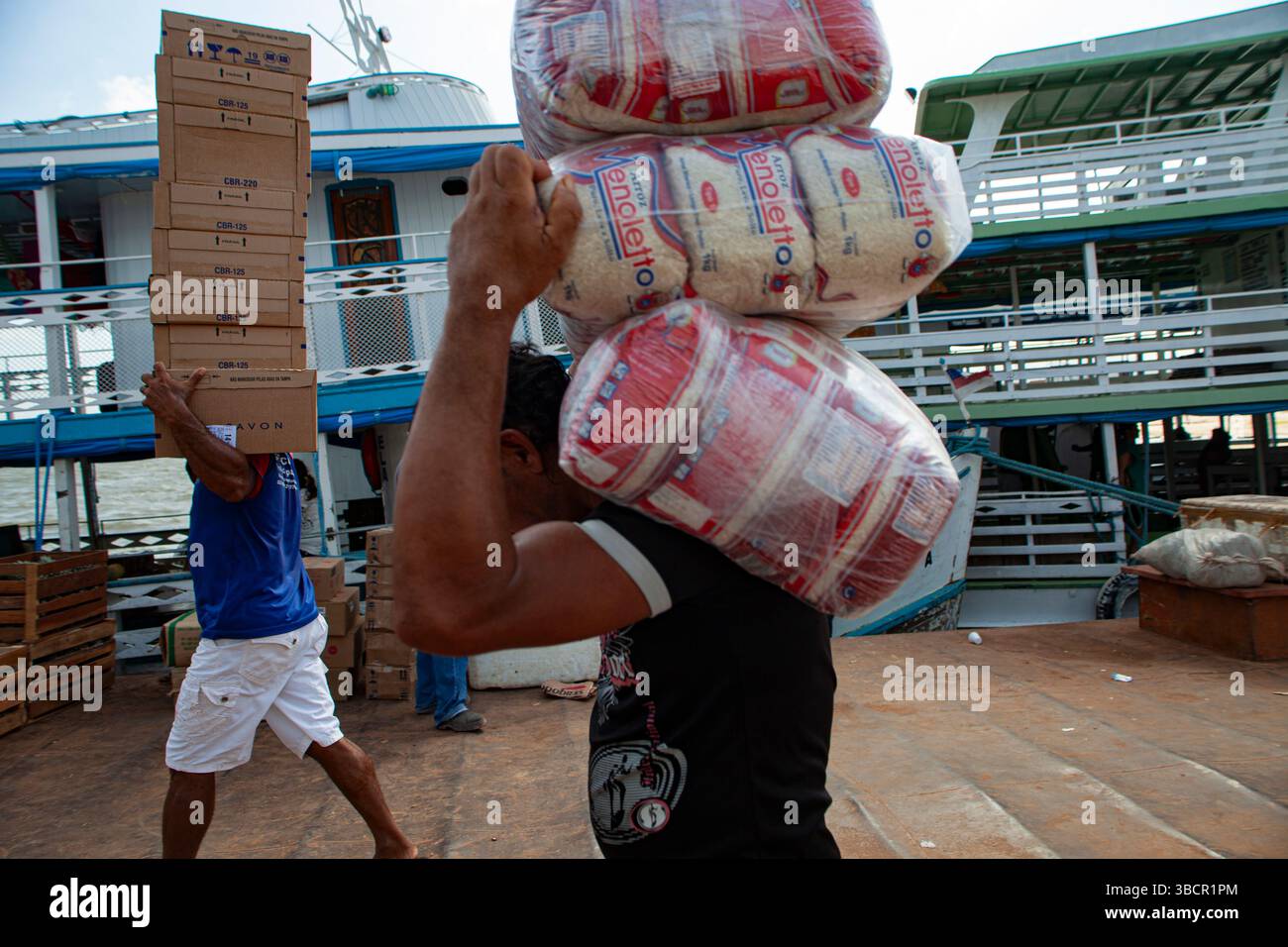 Les dockers chargent diverses marchandises (cosmétiques Avon et paquets de riz) sur les bateaux à aubes traditionnels amazoniens au port de Santarém à Pará, au Brésil. Banque D'Images