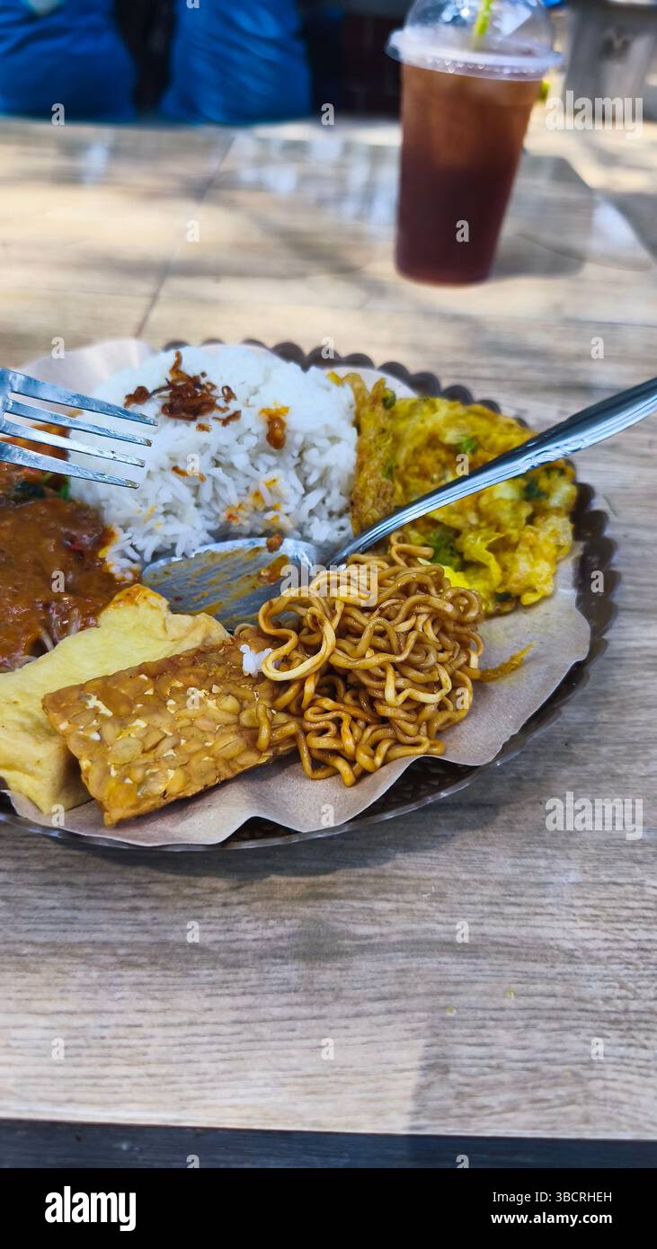 gros plan de riz pecel avec nouilles frites, tempeh, tofu et omelette sur la plage Banque D'Images
