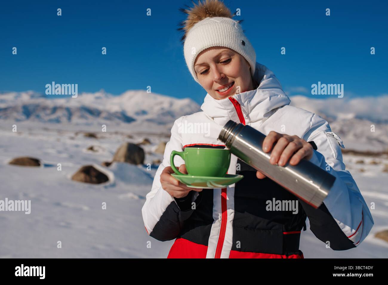 Jeune femme touriste dans les montagnes versant le thé du thermos dans la tasse en hiver Banque D'Images