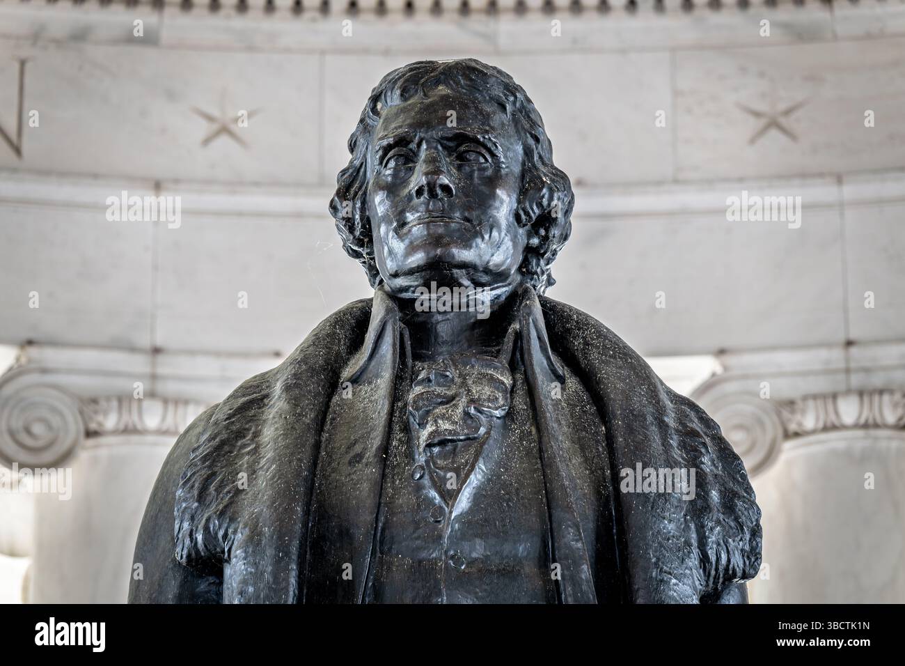 Statue en bronze du mémorial Thomas Jefferson par Rudulph Evans à Washington DC | WASHINGTON D.C., États-Unis — Une vue rapprochée de la tête et des épaules en bronze de Thomas Jefferson capture le manteau à col en fourrure que le sculpteur Rudulph Evans a modélisé d'après le portrait de Rembrandt Peale de 1805, lui-même une référence à une pelisse en peau de loup offerte à Jefferson par le patriote polonais Tadeusz Kościuszko. La statue de 19 pieds (5,8 m), installée en 1947, se dresse au centre de la rotonde inspirée du Panthéon de John Russell Pope, faisant face à la Maison Blanche. Banque D'Images