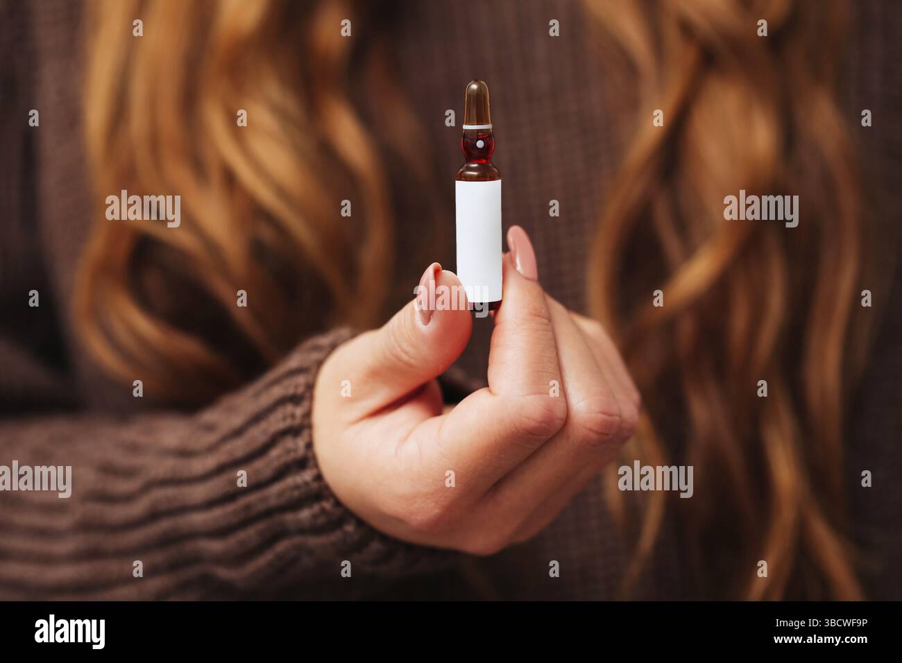 Femme tenant l'ampoule de médecine. Petit flacon en verre avec liquide rouge. Concept de produit pharmaceutique. Dose de traitement de santé. Soins thérapeutiques médicaux. Banque D'Images