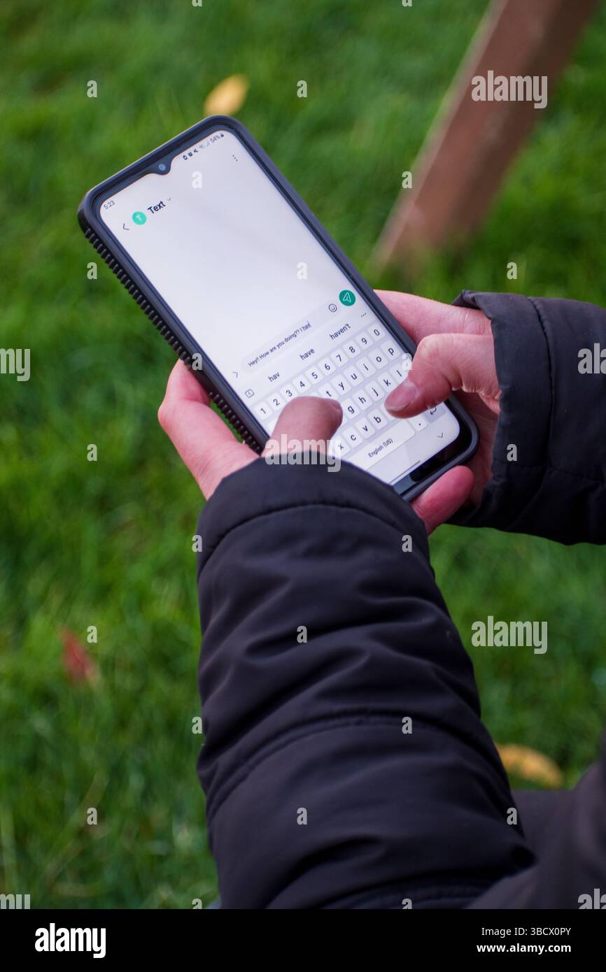 Salt Lake City, UT, États-Unis – 18 mai 2025 : une femme tient un smartphone, concentrée sur l'envoi d'un message texte, capturant la communication moderne en action. Banque D'Images