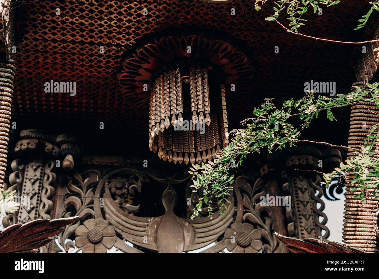 Lustre ornemental en bois dans le pavillon traditionnel du temple thaïlandais riche en éléments floraux sculptés et symbolisme sacré brillent sous le plafond à motifs Banque D'Images