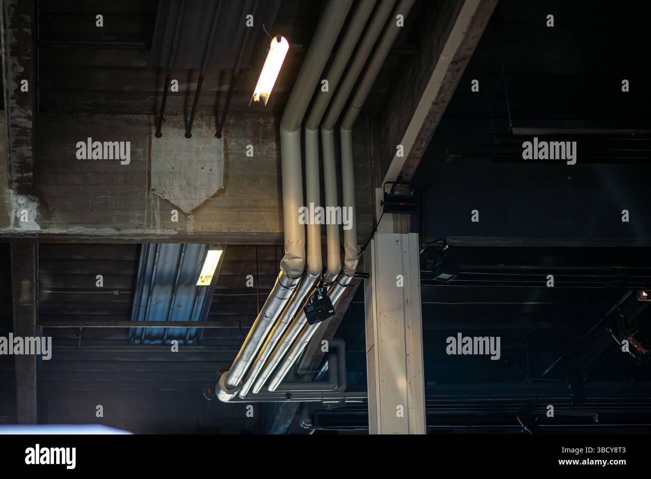 Une vue détaillée du câblage et des connexions d'un système électronique installés directement sur un plafond en béton brut dans un cadre architectural moderne. Banque D'Images