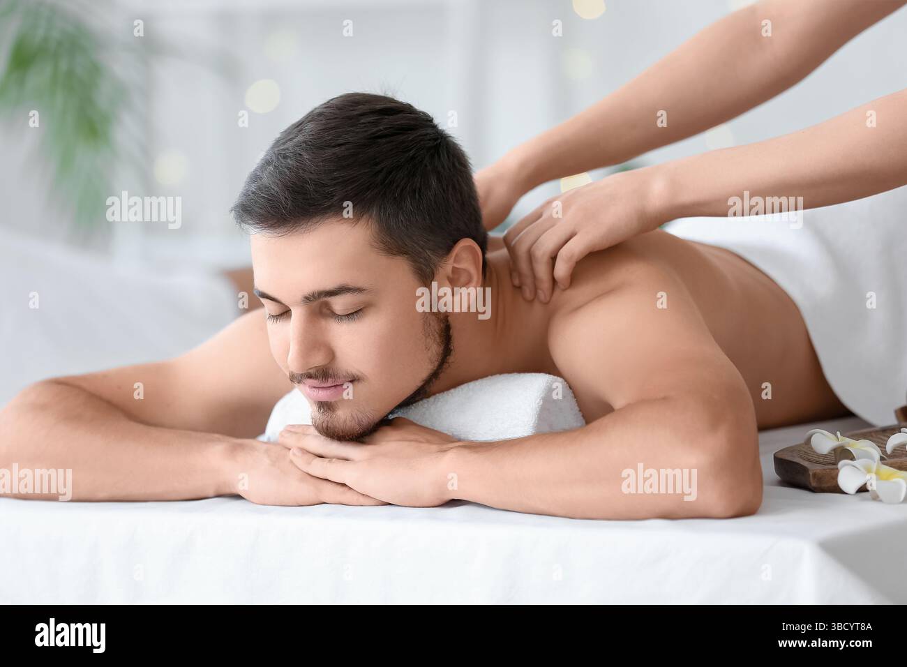 Jeune homme se faisant masser dans le salon de spa Banque D'Images