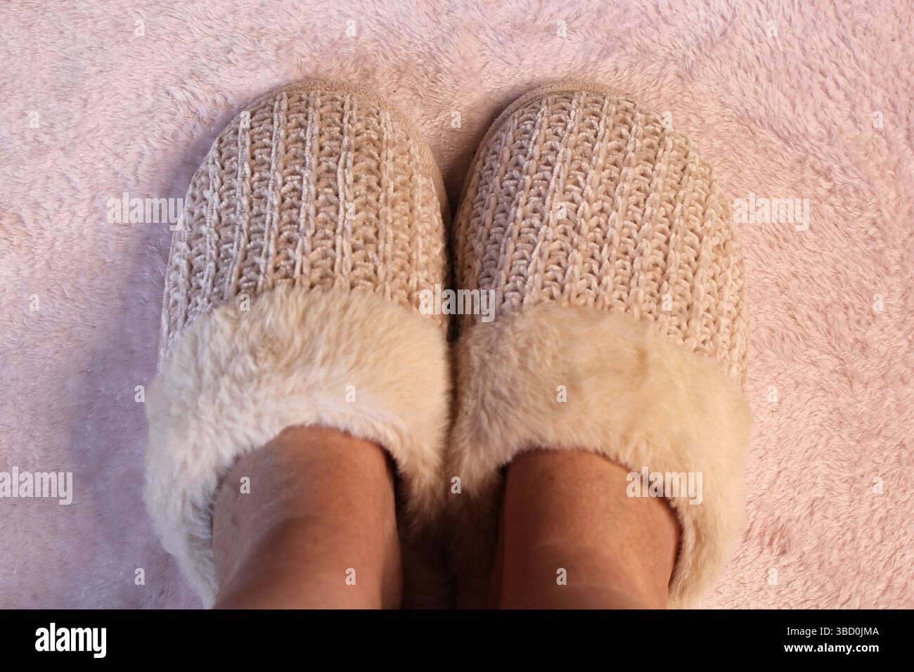 Pantoufles rose pâle avec un fond de tapis en peluche Banque D'Images