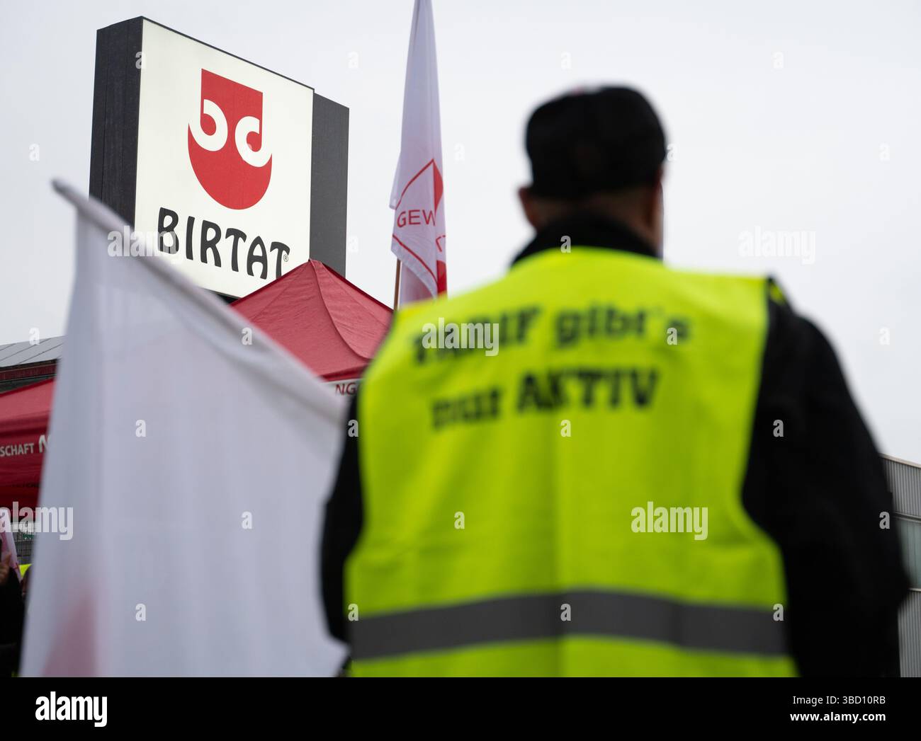 Murr, Allemagne. 22 mai 2025. Un attaquant se tient debout avec un drapeau devant l'usine de kebab Birtat. La grève a été déclenchée par le Syndicat de l'alimentation, des boissons et de la restauration (NGG) parce que les négociations précédentes sur la première convention collective ont échoué. Crédit : Markus Lenhardt/dpa/Alamy Live News Banque D'Images
