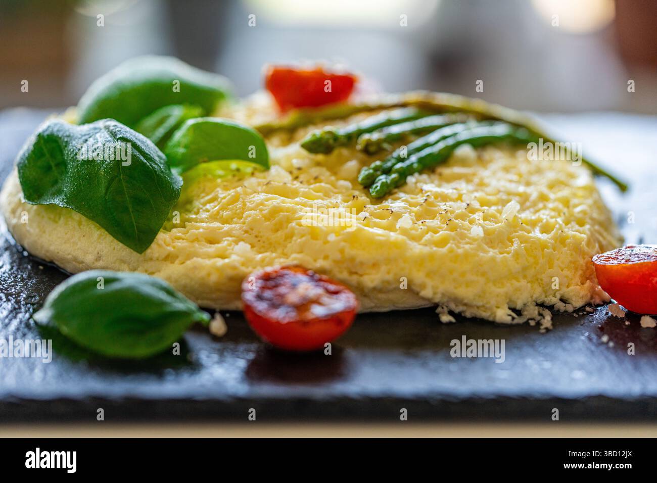 Omelette aux asperges cuites au four, tomates et basilic. Gros plan, arrière-plan. Pour une utilisation dans les menus et les bannières. Le concept d'un petit déjeuner délicieux et sain. Banque D'Images