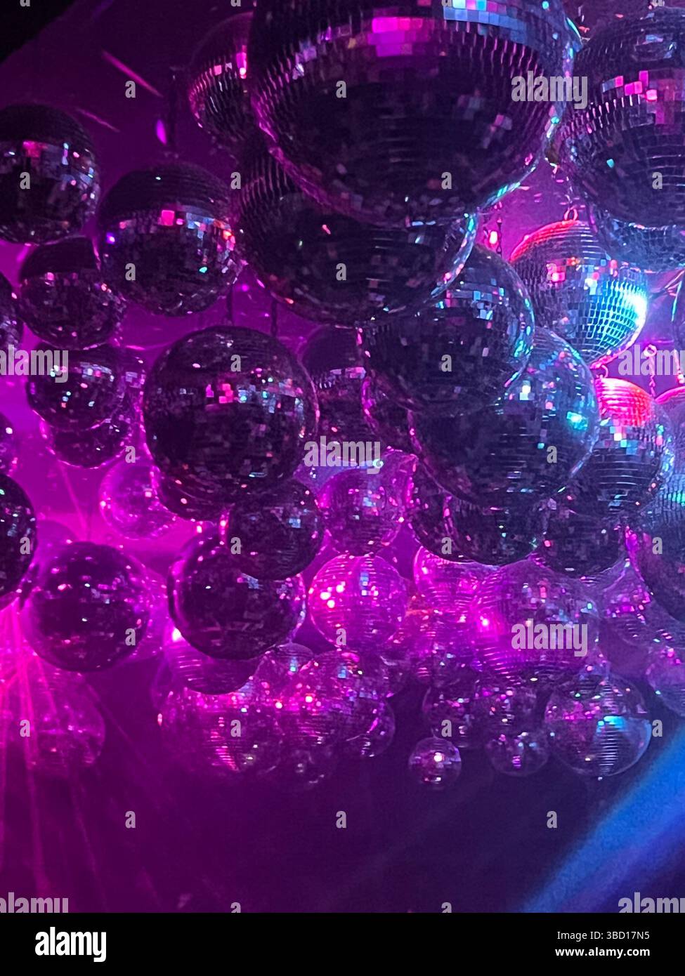 Affichage vibrant de boules disco suspendues illuminées par des lumières roses et bleues, créant une atmosphère de fête dynamique et festive - parfait pour la vie nocturne, c - Image de stock capturée avec un smartphone