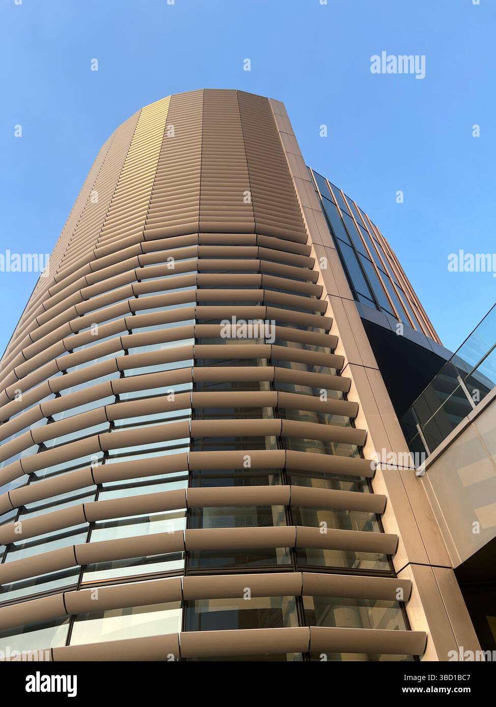 Jakarta, Indonésie-août 2023 : vue en angle bas d'un immeuble de bureaux moderne à l'architecture courbe et aux pare-soleil horizontaux sur un ciel bleu clair. - Image de stock capturée avec un smartphone