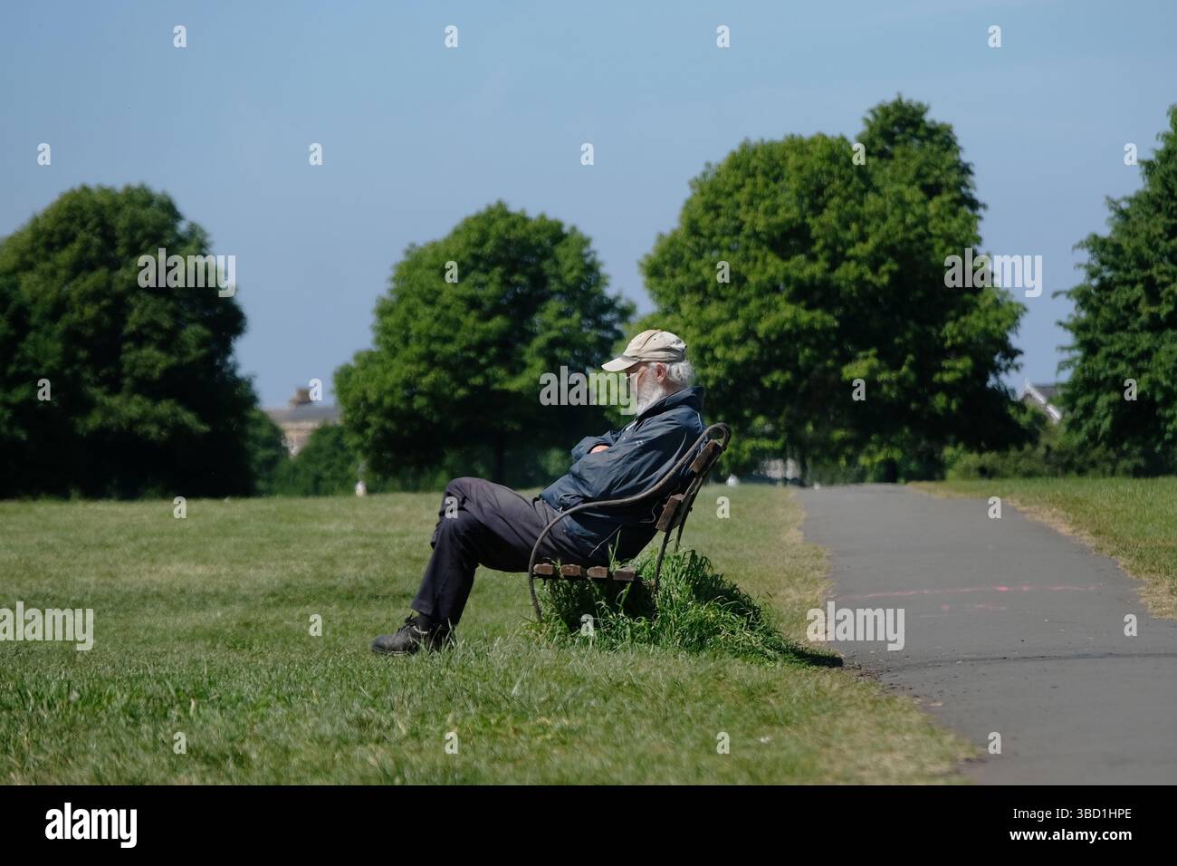Un vieil homme assis sur un banc au soleil. Banque D'Images