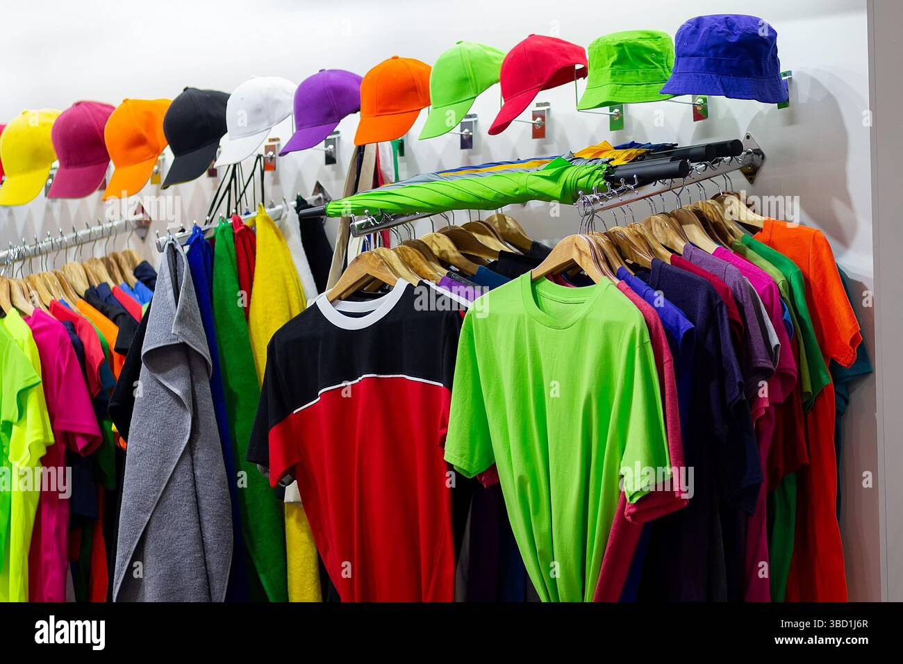 T-shirts multicolores et casquettes de baseball sur la fenêtre d'un magasin de sport. Soldes Banque D'Images