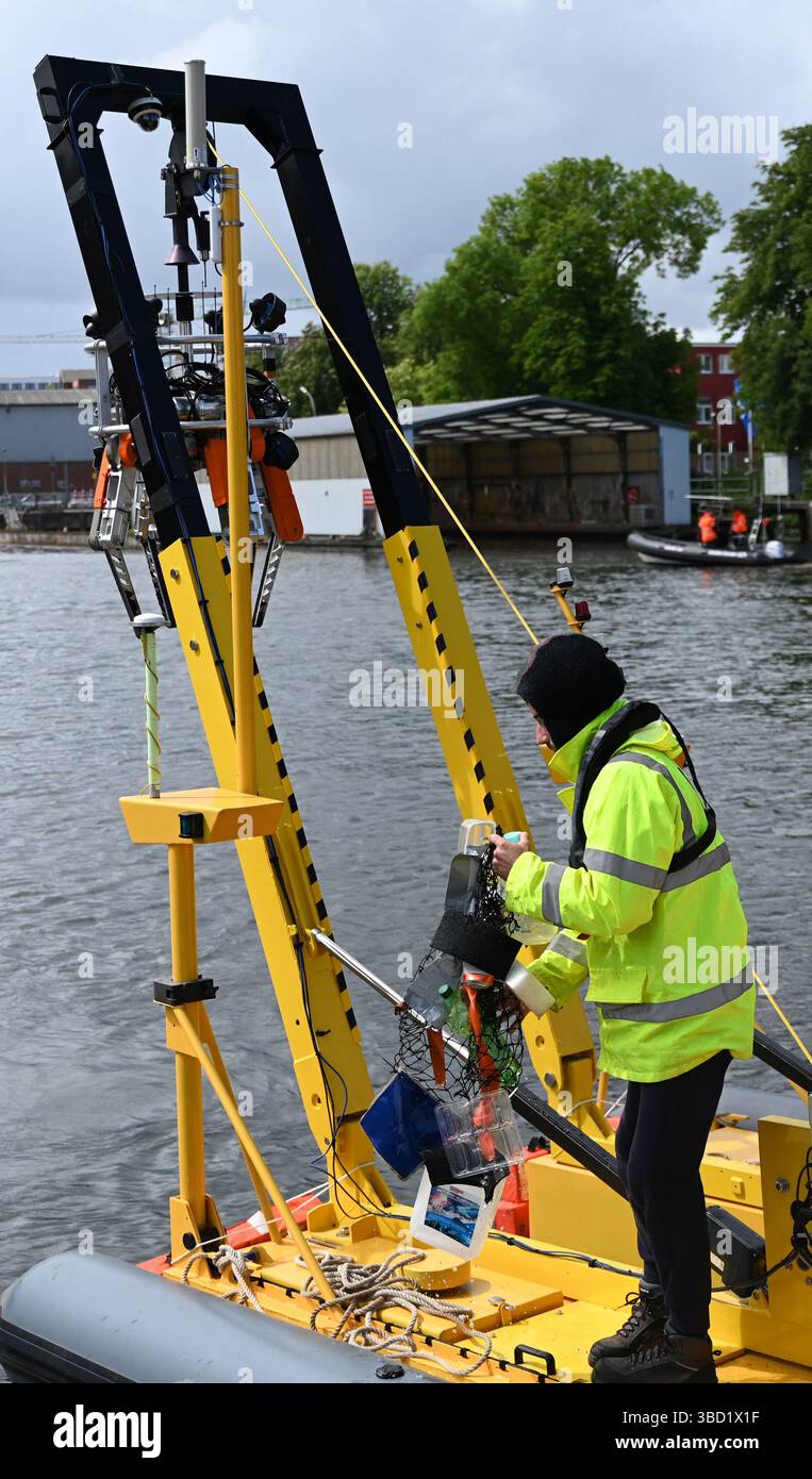 Hambourg, Allemagne. 22 mai 2025. Un employé récupère les déchets de l'eau lors d'un événement de presse à Hambourg-Harburg. Le système robotique « SeaClear2.0 » offre une approche soutenue par l'IA pour lutter contre la pollution marine. À l'aide de véhicules de surface sans pilote, de robots sous-marins télécommandés et d'un drone, les déchets peuvent être collectés des fonds marins de manière ciblée. Crédit : David Hammersen/dpa/Alamy Live News Banque D'Images