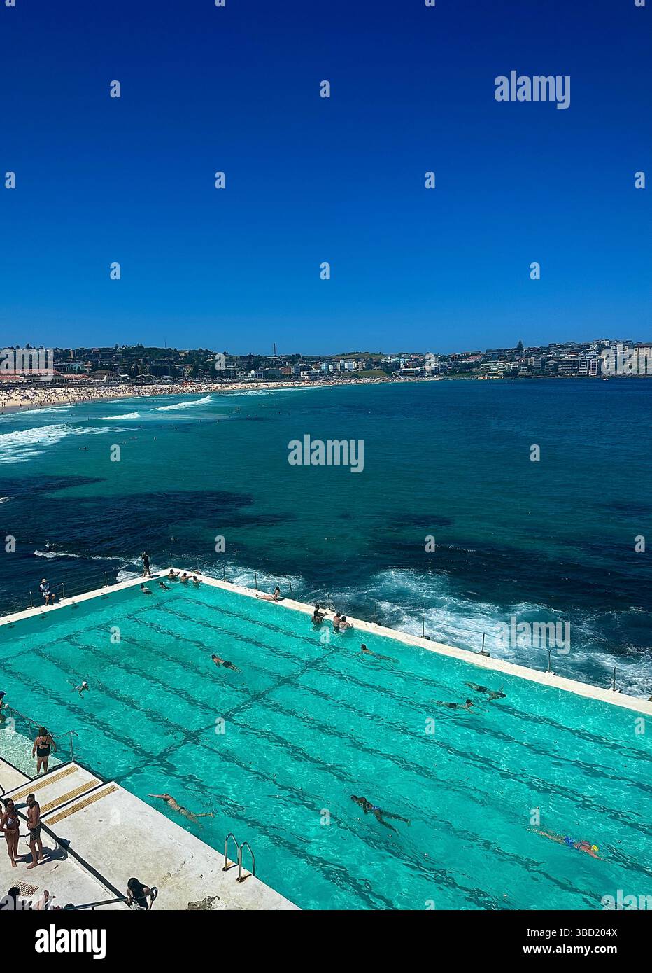 Nageurs profitant de l'emblématique piscine océanique Bondi icebergs avec vue panoramique sur Bondi Beach et l'océan Pacifique turquoise étincelant sous un blu clair - Image de stock capturée avec un smartphone