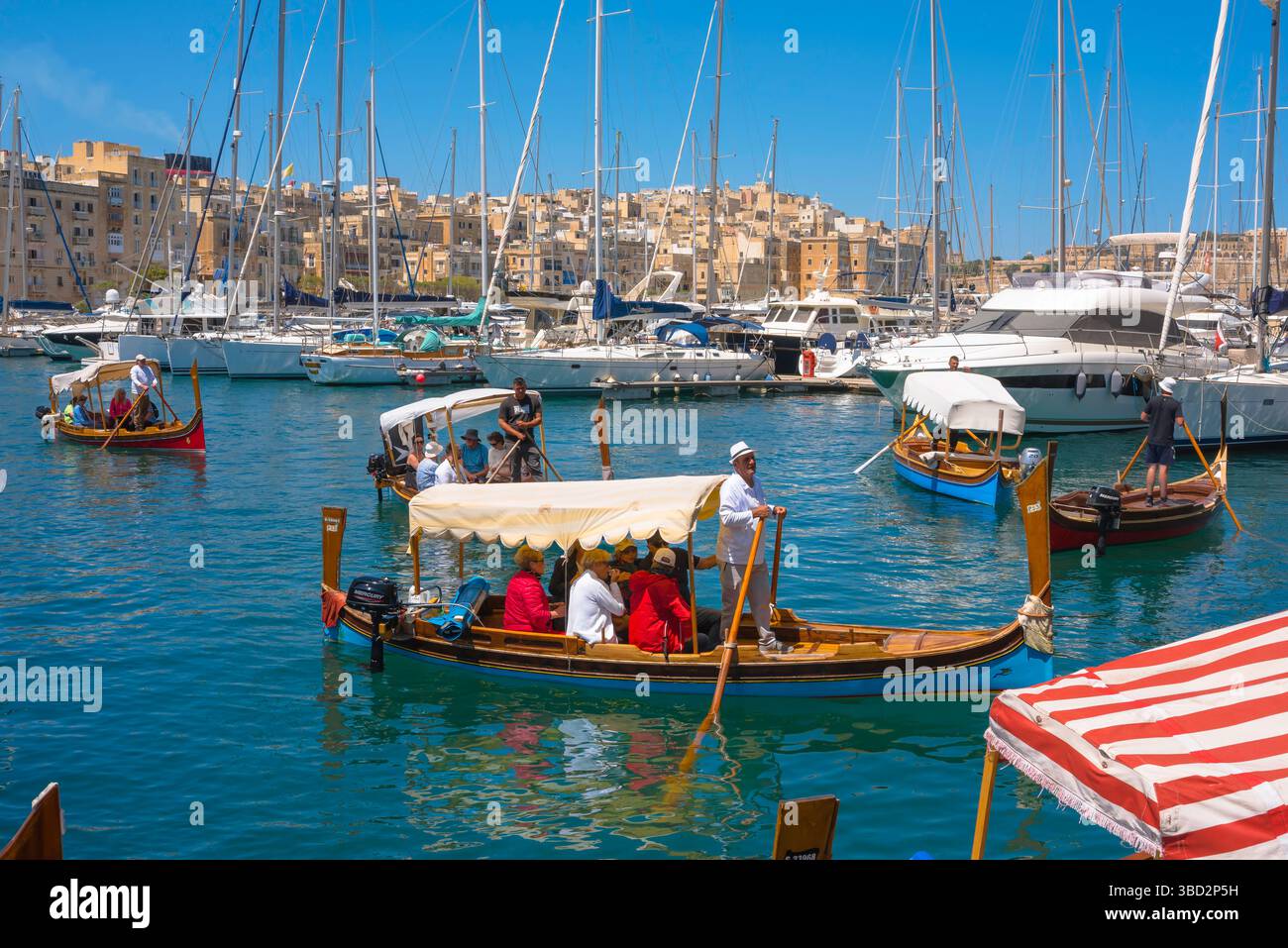 Bateau-taxi Valletta, vue sur les bateaux-taxis maltais traditionnels (dghajsa) de la Valette arrivant au front de mer de la marina à Vittoriosa, Malte Banque D'Images
