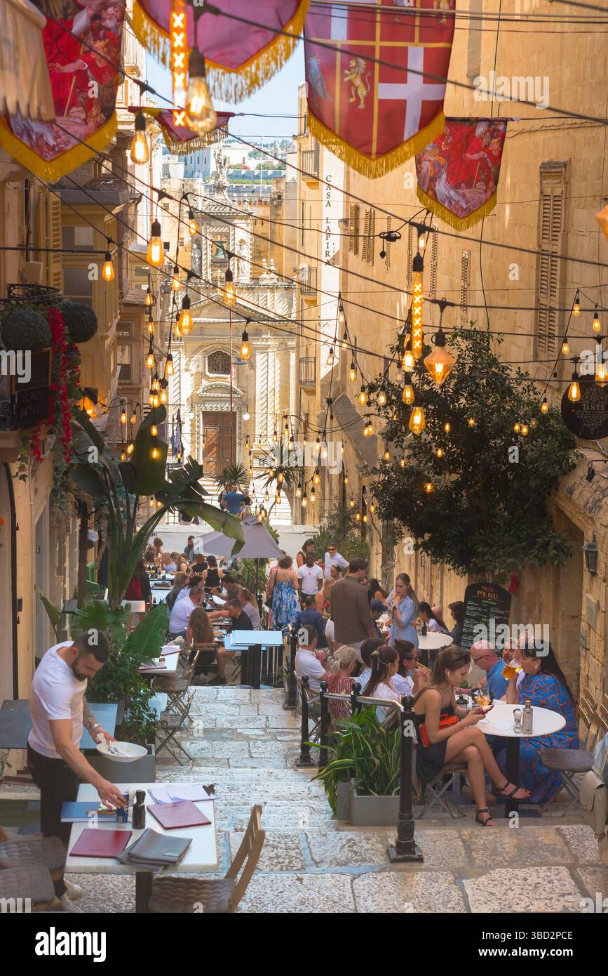 Café de la Valette, vue en été d'une rue populaire contenant des cafés et des restaurants dans le centre historique de la ville de la Valette, Malte Banque D'Images