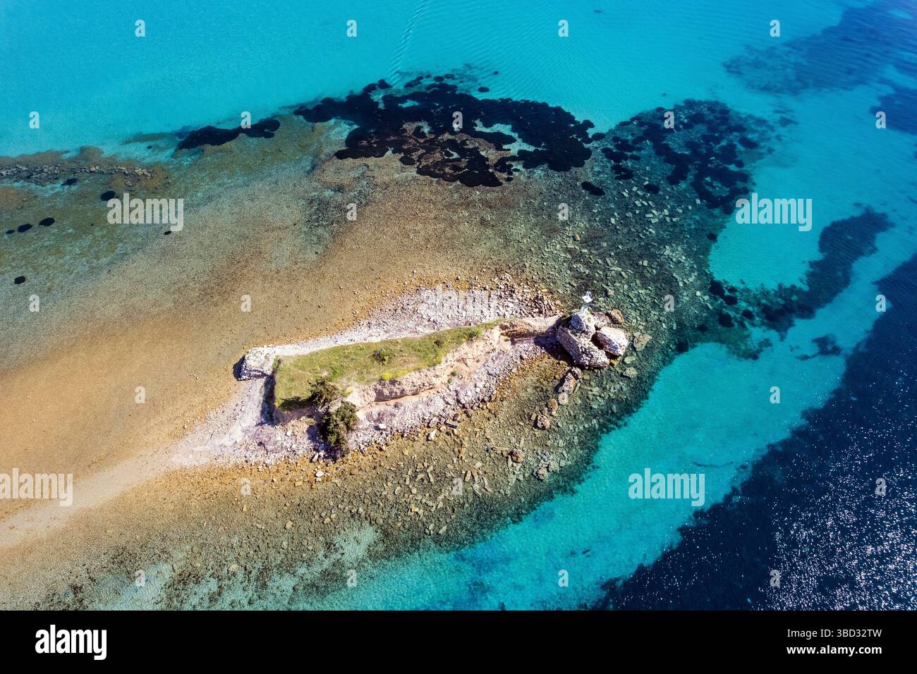 Drone vue d'un minuscule îlot avec des ruines antiques et des rivages rocheux près de Potidea, Halkidiki, entouré par des eaux turquoise peu profondes et bleu profond de la mer Égée. Banque D'Images