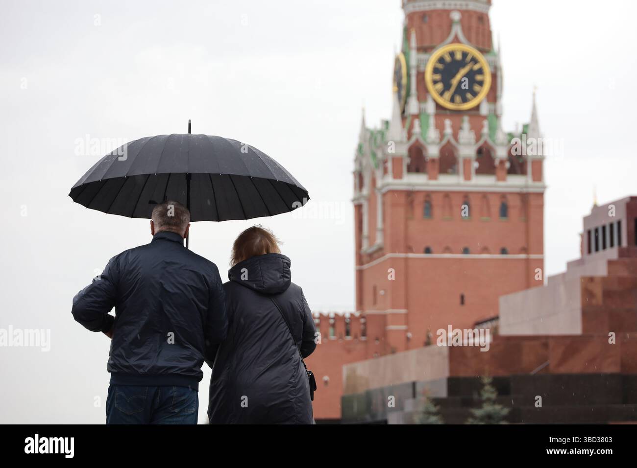 Couple avec un parapluie marchant sur la place Rouge à Moscou sur fond de tour du Kremlin, pluie en ville Banque D'Images