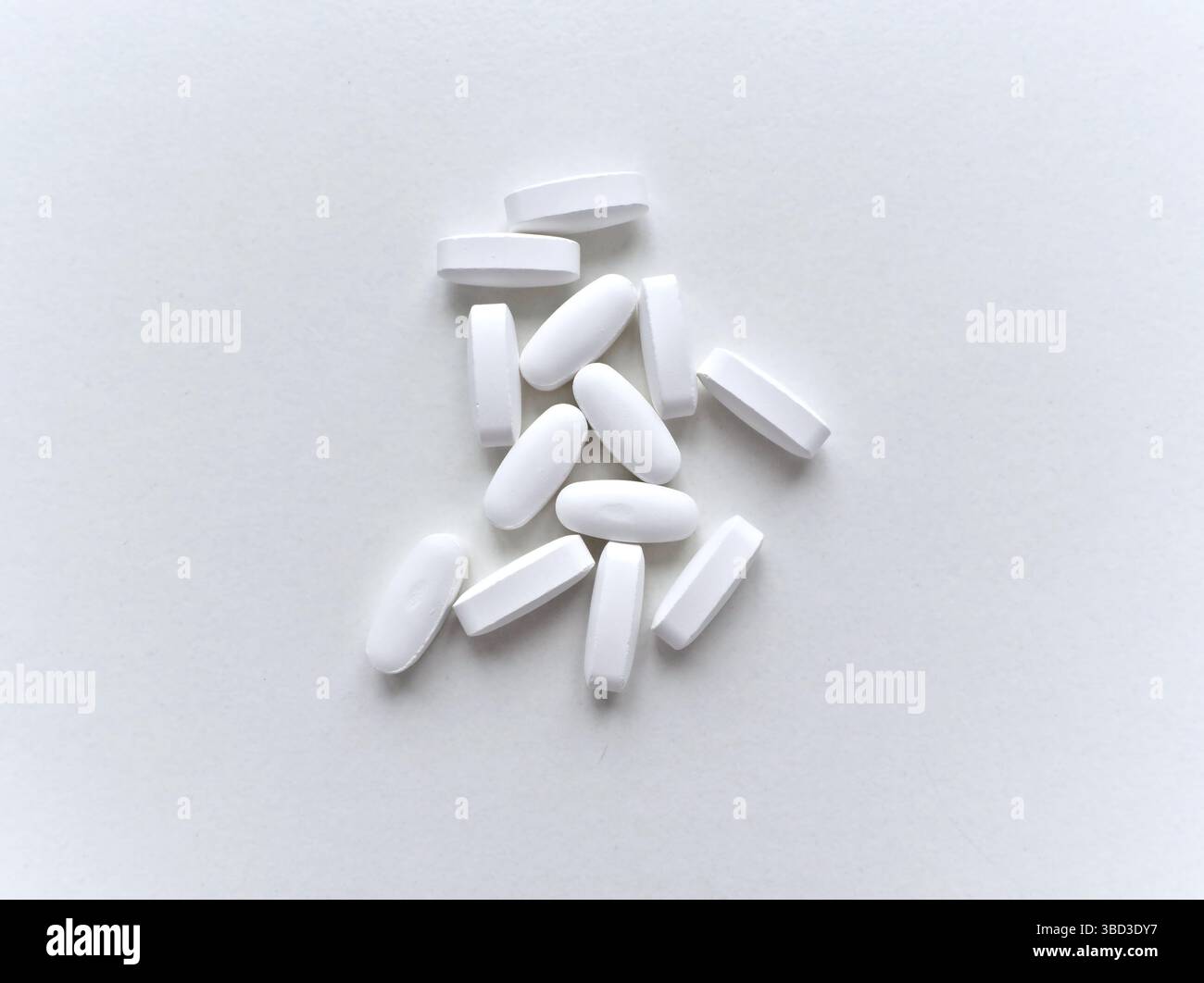 Une pile de pilules blanches sur un fond blanc. Les pilules sont petites et blanches, et elles sont dispersées à travers la surface. Concept d'organisation et ord Banque D'Images