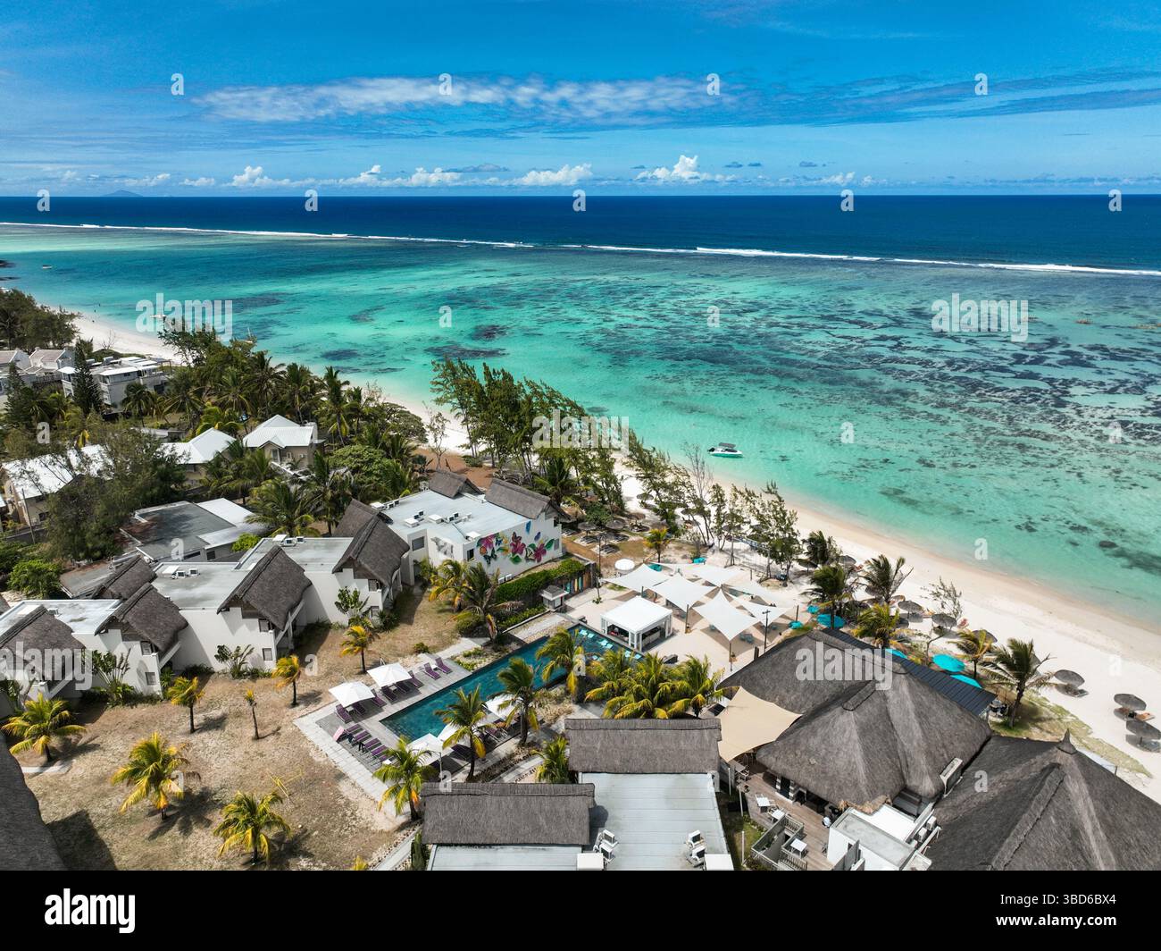 Vue drone sur l'hôtel et les villas en bord de mer entourés d'eau claire et d'arbres Banque D'Images