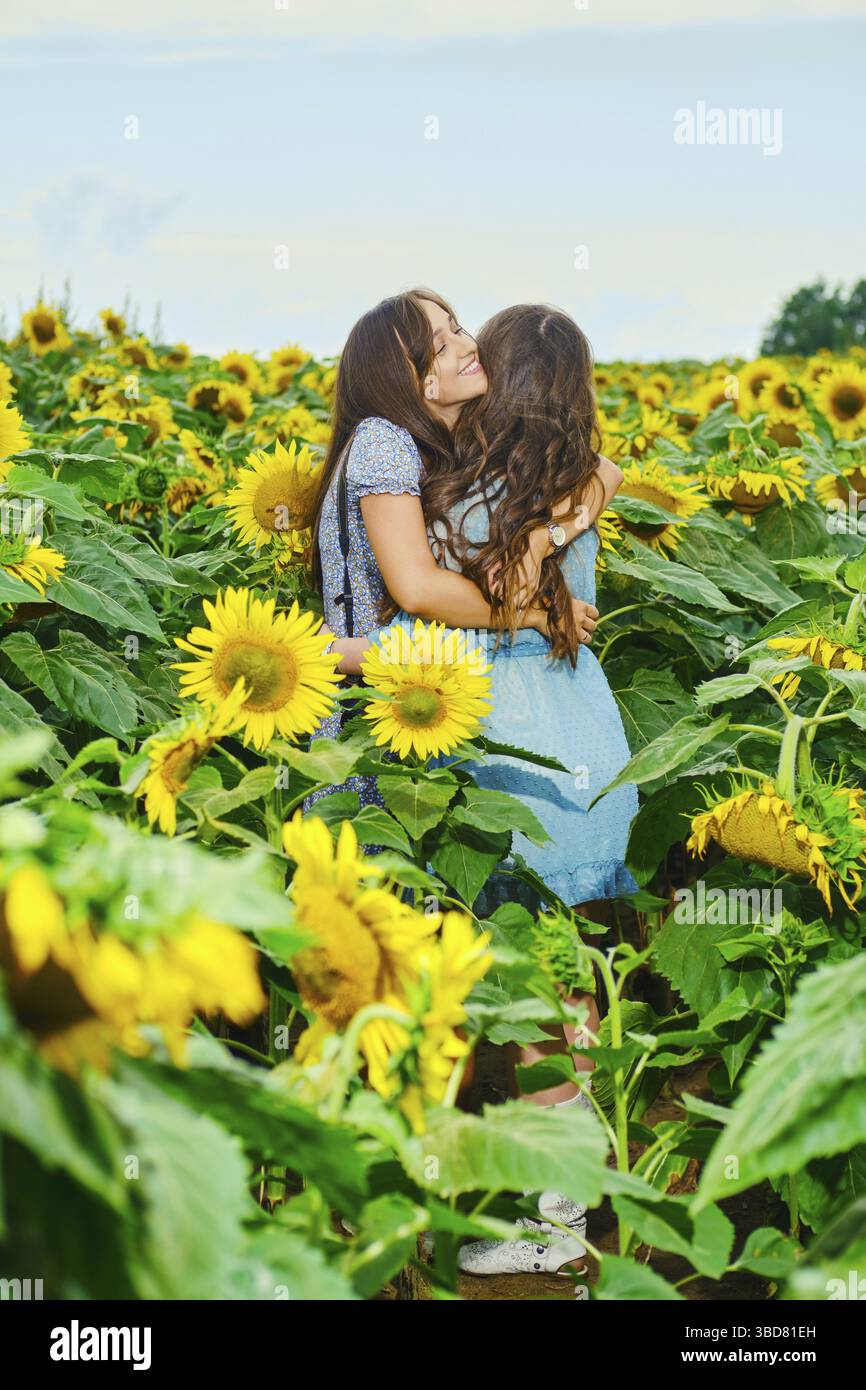 Deux amies se embrassent sur le champ de tournesol Banque D'Images