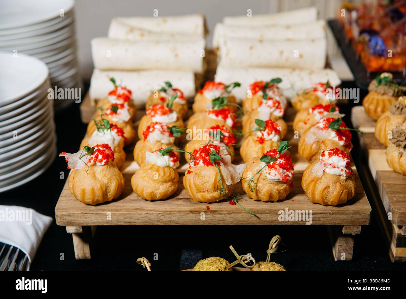 Canapés de fête élégants avec bouffées dorées à la crème garnies de mousse salée et recouvertes de caviar rouge et de microverts. Banque D'Images