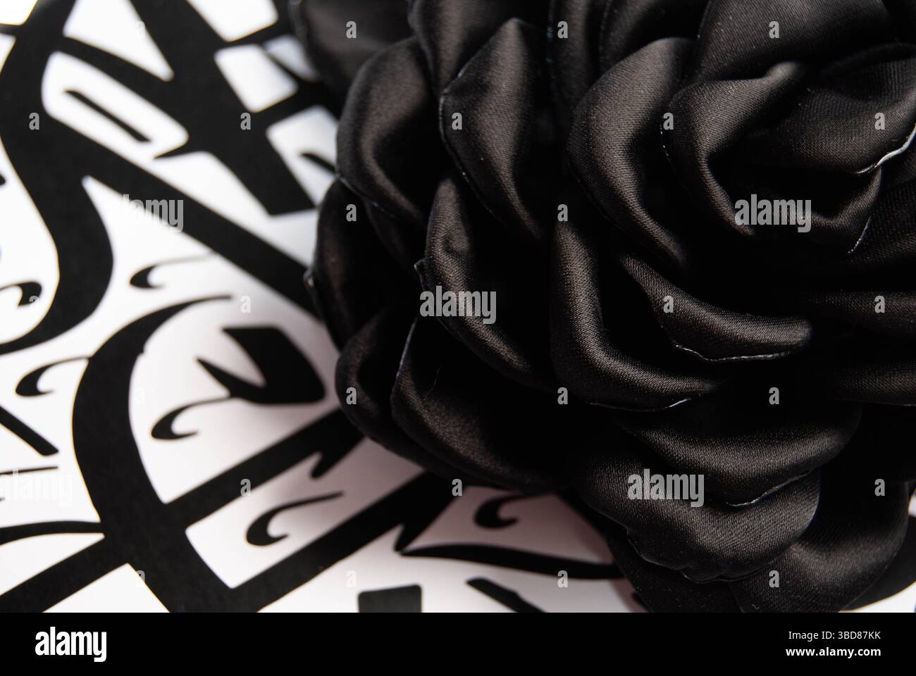 Rose noire placée artistiquement sur fond d'écriture arabe foncé. Banque D'Images