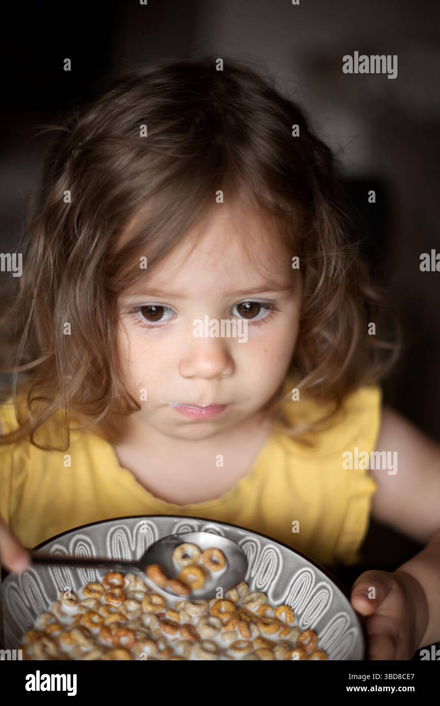 Petite fille mange des céréales complètes pour le petit déjeuner à la maison. Banque D'Images