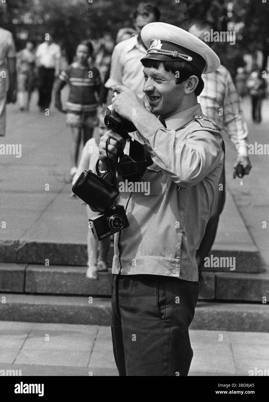 Russian Man in Uniform aide les touristes russes à prendre des photos avec leurs appareils photo lors de leurs visites à Berlin Banque D'Images