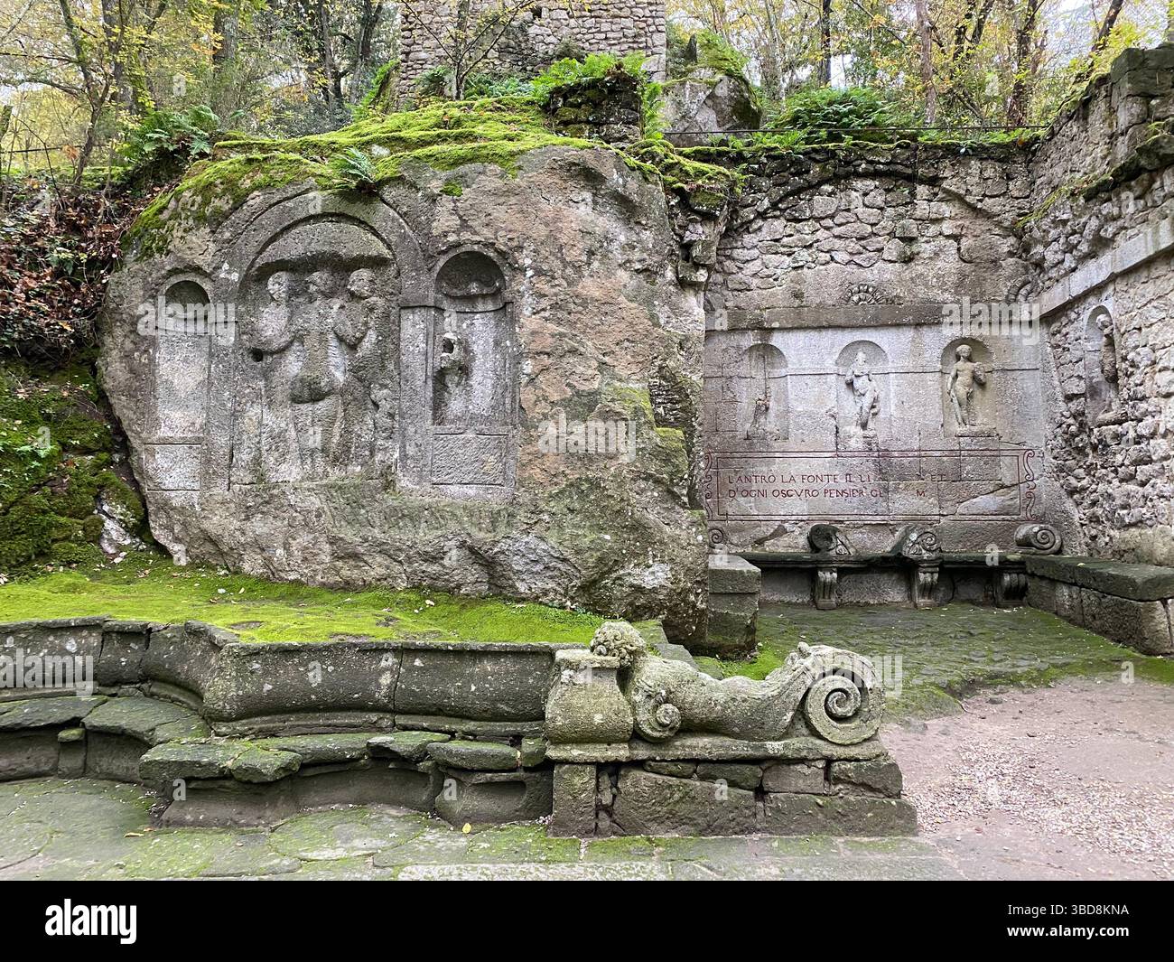 Sculptures en pierre recouvertes de mousse ornant d'anciennes sculptures dans le luxuriant Sacred Grove de Bomarzo, révélant des pierres historiques complexes au milieu d'un paysage verdoyant Banque D'Images
