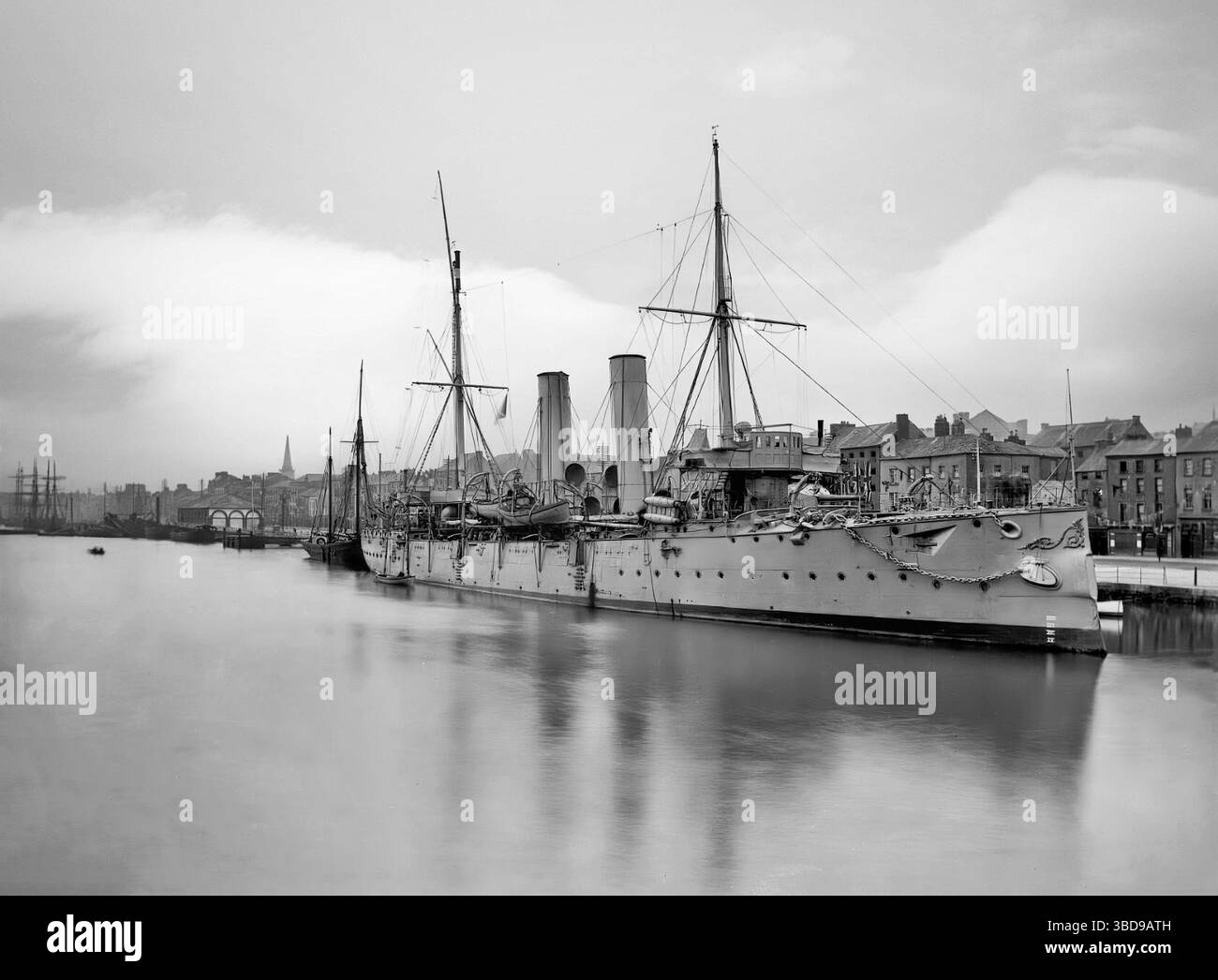 Une photographie du début du XXe siècle du HMS Melampus, un croiseur protégé de classe Apollo de la Royal Navy qui a servi de 1890 à 1910 amarré aux quais bordant la rivière Suir alors qu'elle traverse Waterford City, en Irlande. Banque D'Images