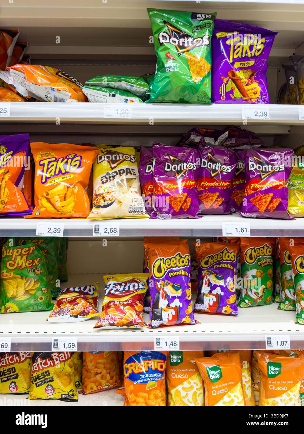 Différentes marques de snacks emballés Doritos, Takis et Cheetos sur les étagères des supermarchés avec étiquettes de prix visibles Banque D'Images