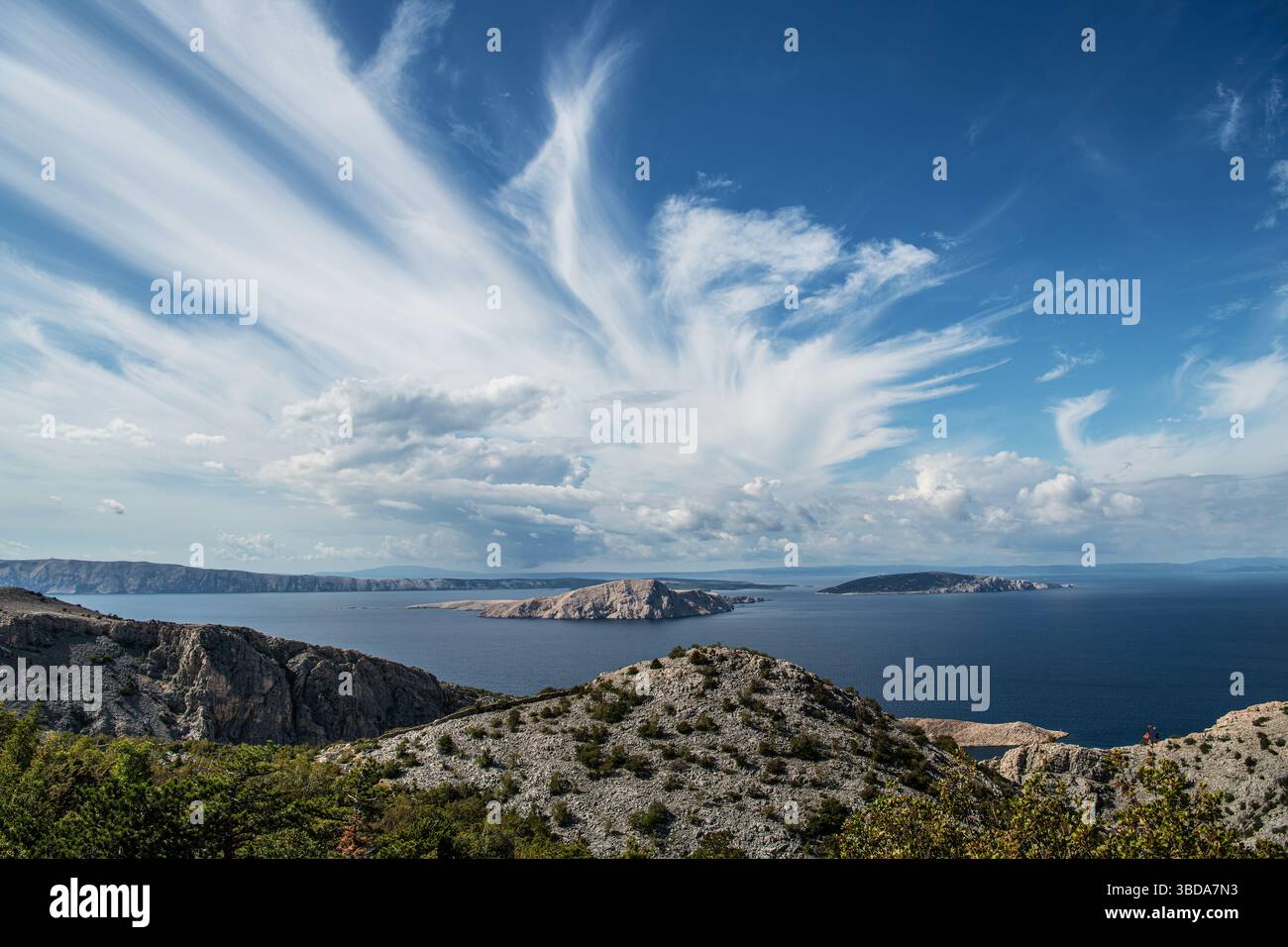 Vue imprenable sur la côte croate avec des collines rocheuses, des eaux bleues sereines et un ciel étendu rempli de nuages moelleux. Une maman tranquille Banque D'Images