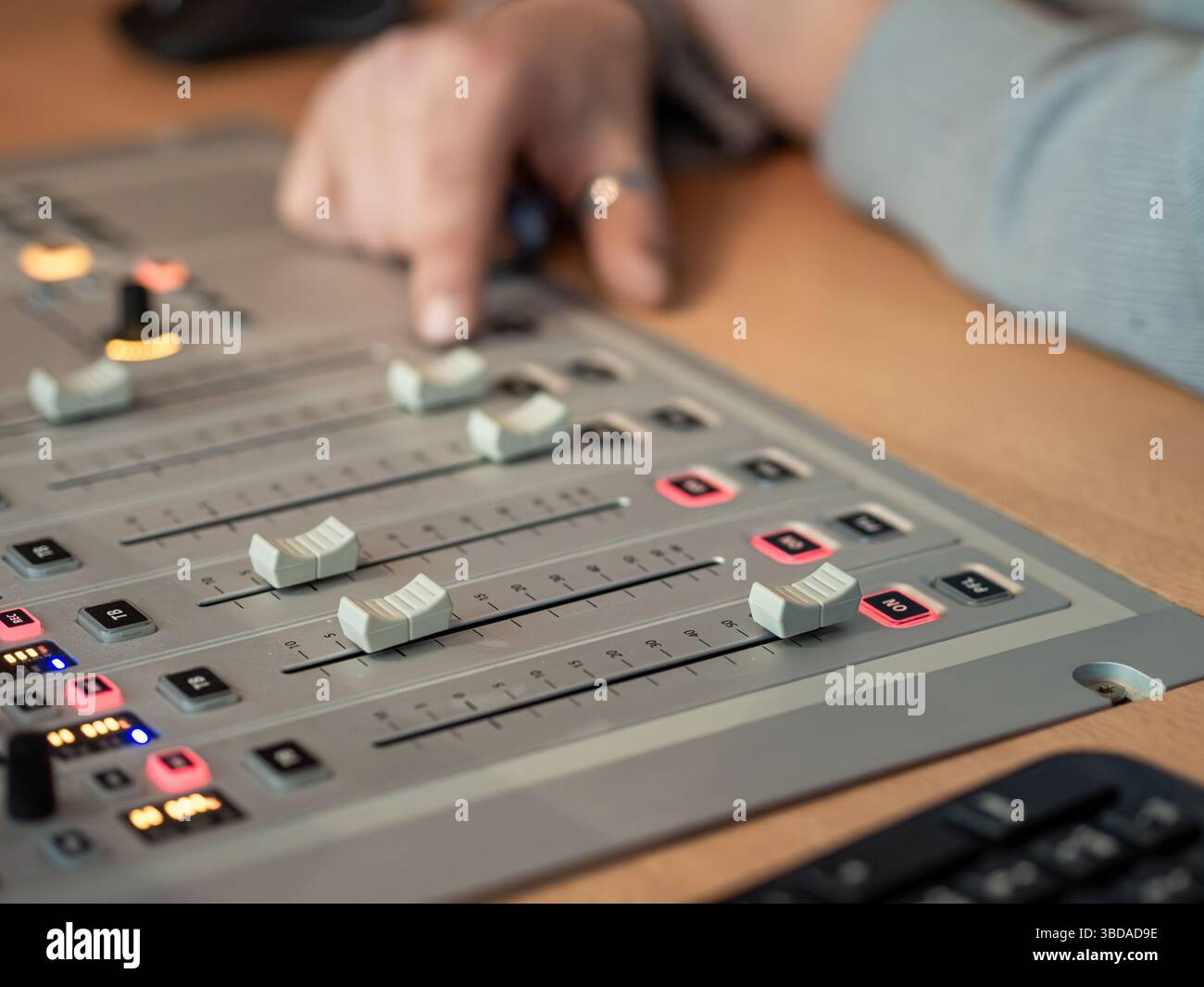 Un technicien du son ajuste habilement les niveaux audio sur une console de mixage dans un studio d'enregistrement. L'environnement est axé sur l'amélioration de la qualité sonore du Banque D'Images