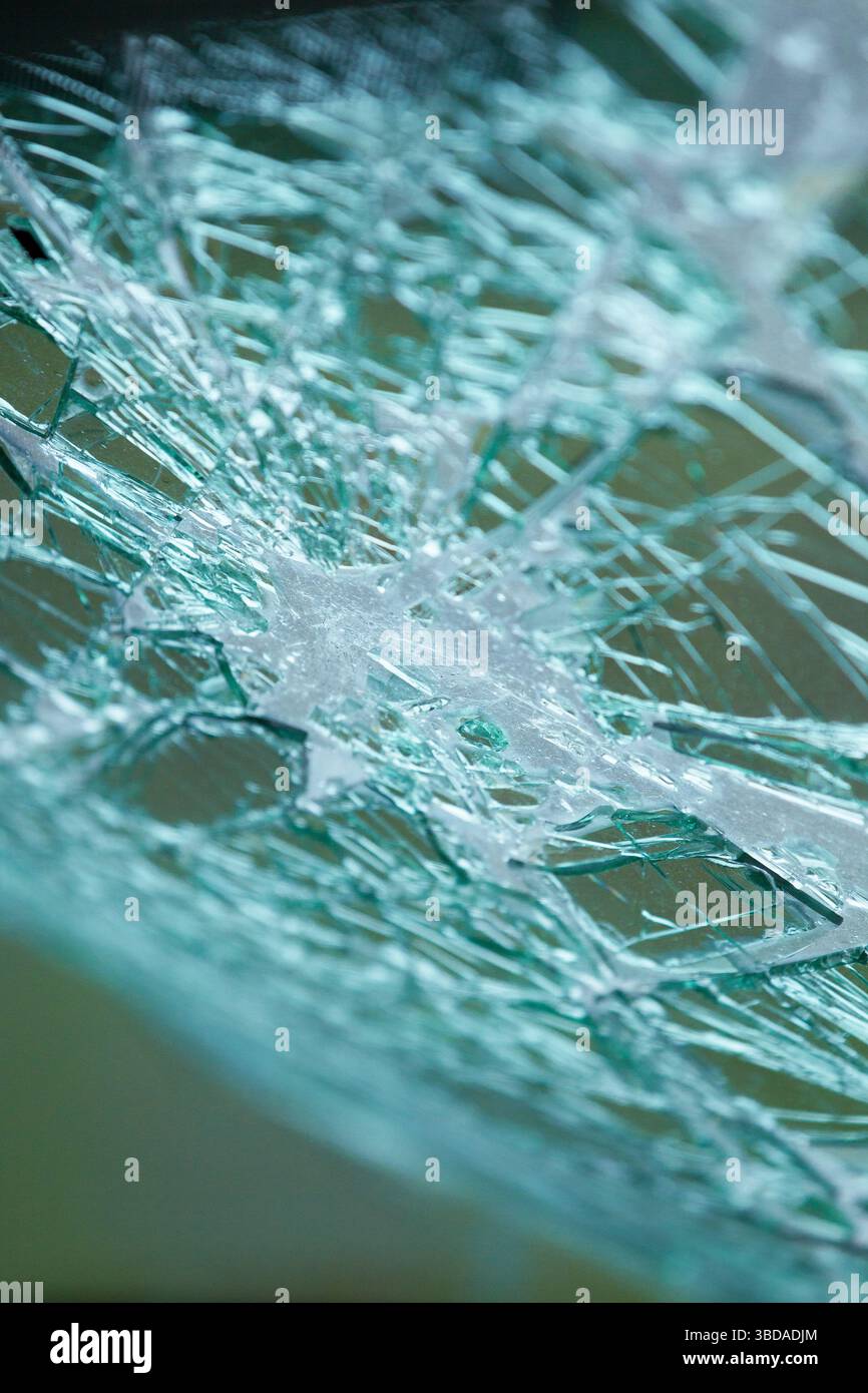 Vue détaillée du verre de sécurité brisé avec des fissures radiales. Fissures et éclats dans la vitre de voiture endommagée. Banque D'Images